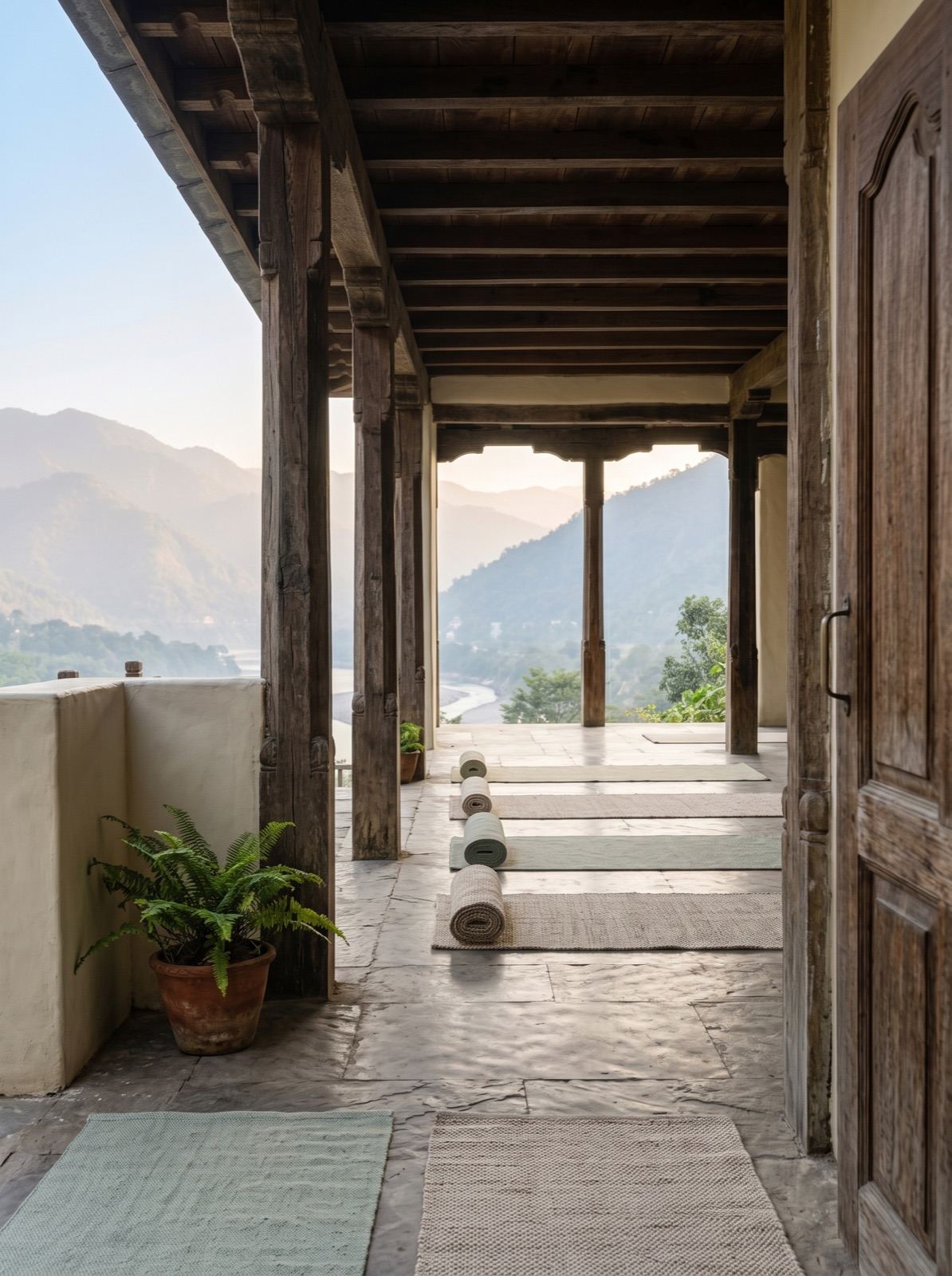 Open retreat practice corridor in Rishikesh with mats facing the mountain and river landscape